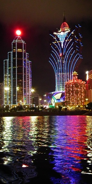 Photo de loin d'une ville lumineuse la nuit avec le reflet des lumères sur l'eau