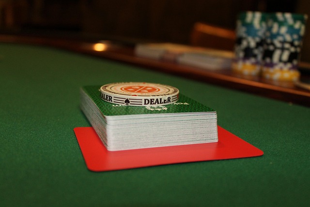 Table de poker avec un paquet de cartes au dos vert posé sur une cutcard rouge et un jeton dealer sur le dessus.
